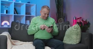 一位使用手机应用程序的老人坐在沙发上，一位老人发短信打字，手持智能手机看手机屏幕